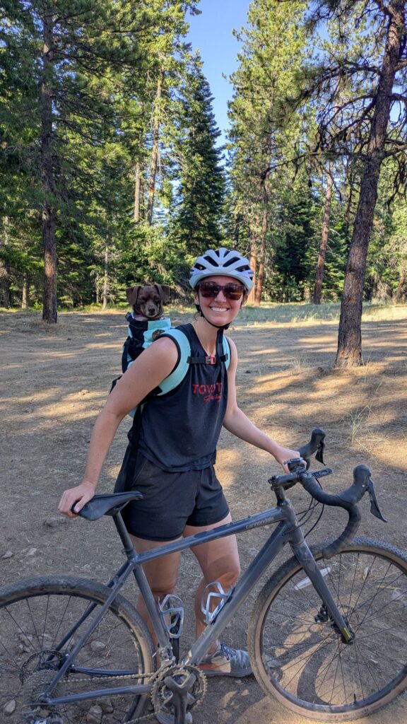 Dog in backpack and woman biking